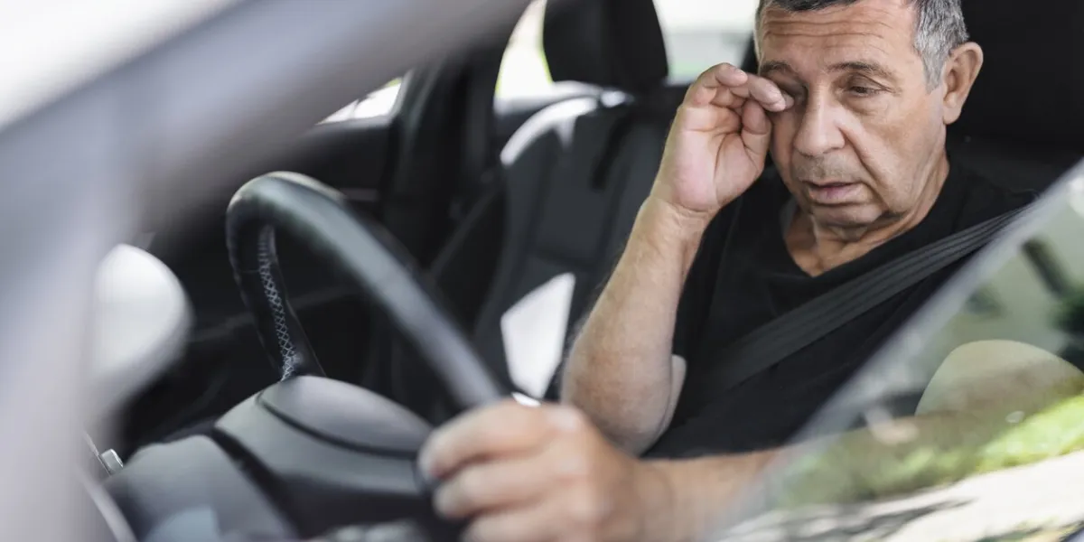 tired pensioner in his 70s, dring in a car