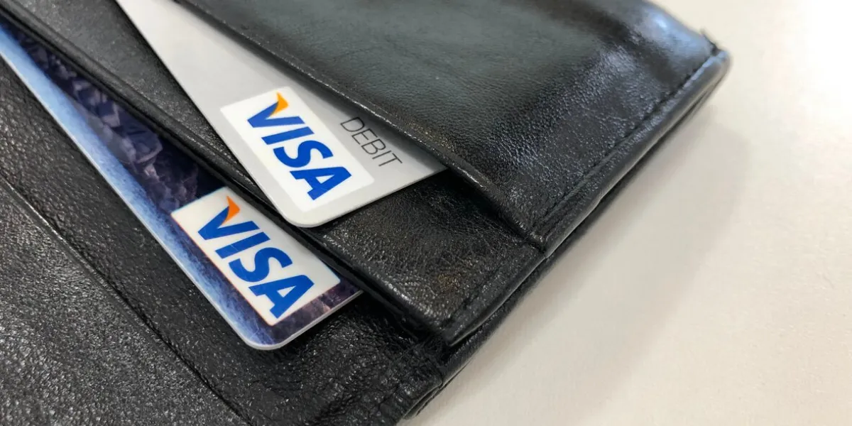 munich, germany bavaria - may 22, 2021  visa credit and debit cards in a black leather wallet with a white table surface background
