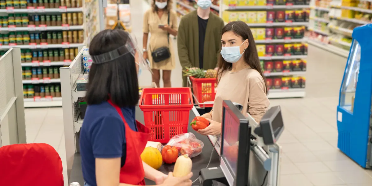customers in supermarket checkout queue wearing masks and following social distancing rule during covid-19 quarantine time