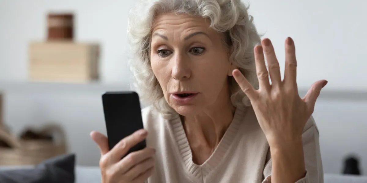 angry shocked mature phone user staring at screen in surprise elderly lady worried about app error, data stealing, scam, bad news, problems with smartphone annoyed woman using cell for video call