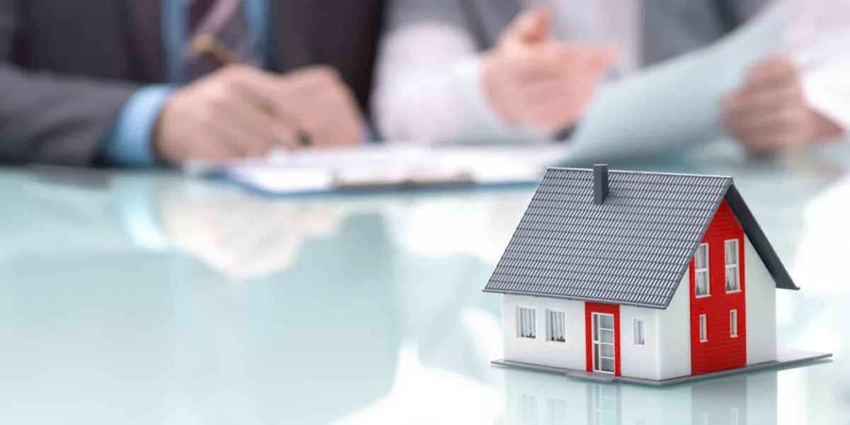 businessman signs contract behind home architectural model