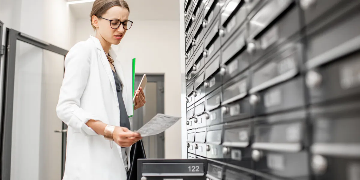 dispirited woman checking bills getting correspondence from the mailboxes in the walk hall of the residential building