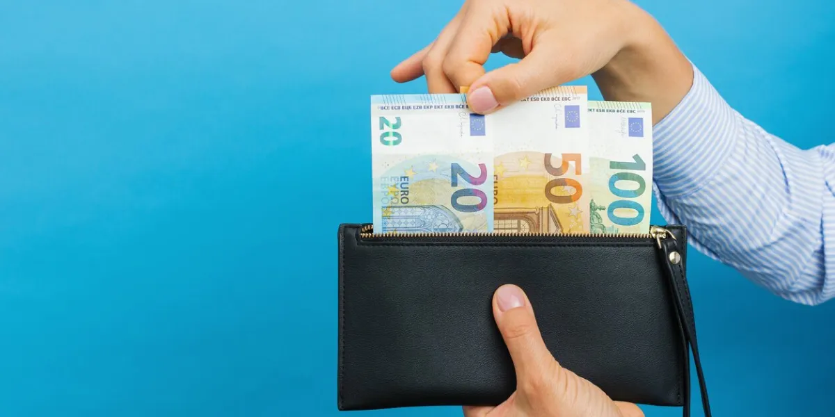 female hands holding black wallet with euro banknotes on a blue background