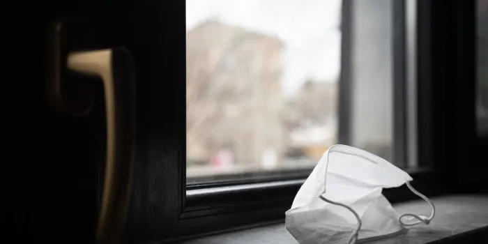 perspective view closeup of medical protection face mask left by the closed window near door handle quarantine concept