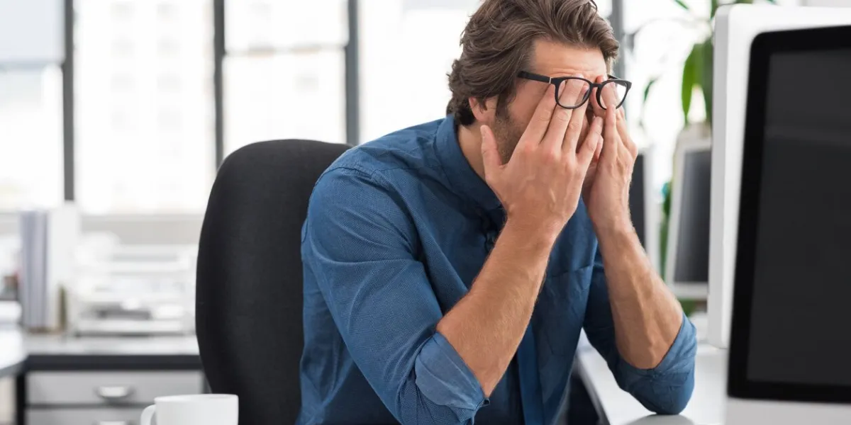 portrait of an upset businessman at desk in office businessman being depressed by working in office young stressed business man feeling strain in eyes after working for long hours on computer