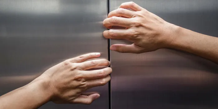 mains de femme essaient d'arrêter les portes de l'ascenseur fermé