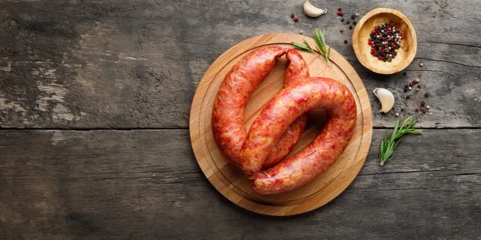 smoked sausage with rosemary and spices on a wooden table top view flat lay copy space for text