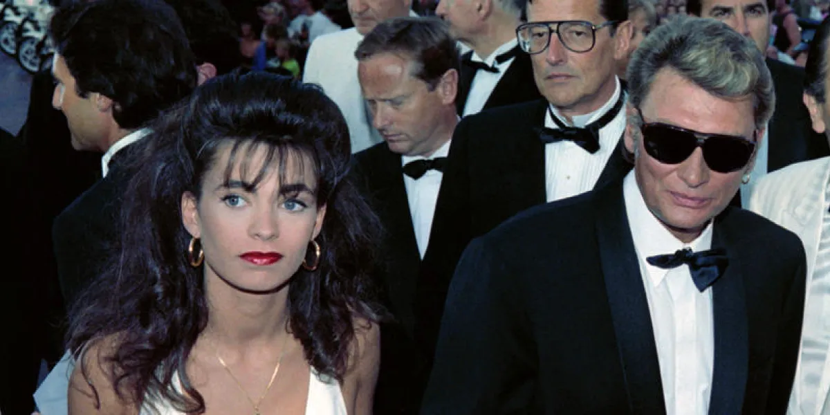 le chanteur johnny hallyday arrive le 10 mai 1990 au festival de cinéma à cannes en compagnie de sa fiancée, adeline blondieau, qu'il doit épouser en juillet, et de son producteur jean-claude camus (2nd plan, avec lunettes) afp photo