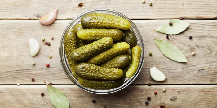 pickled gherkins or cucumbers in bowl on wooden rustic table from above