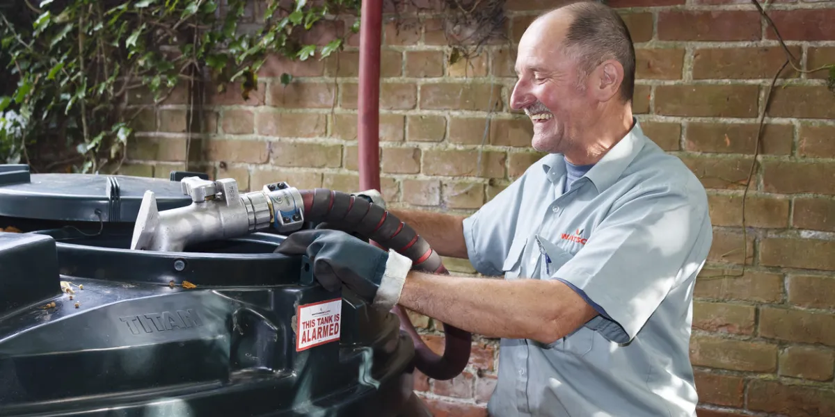 buckingham, uk - september 13, 2014 man filling a bunded oil tank with domestic heating oil (kerosene) at a home in rural england, uk