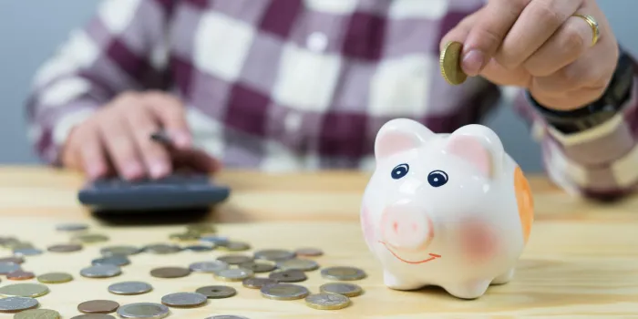 money, home, finance and relationships concept -man with pig bank sitting on desk,businessman putting coin into the piggy banks,vintage color morning light