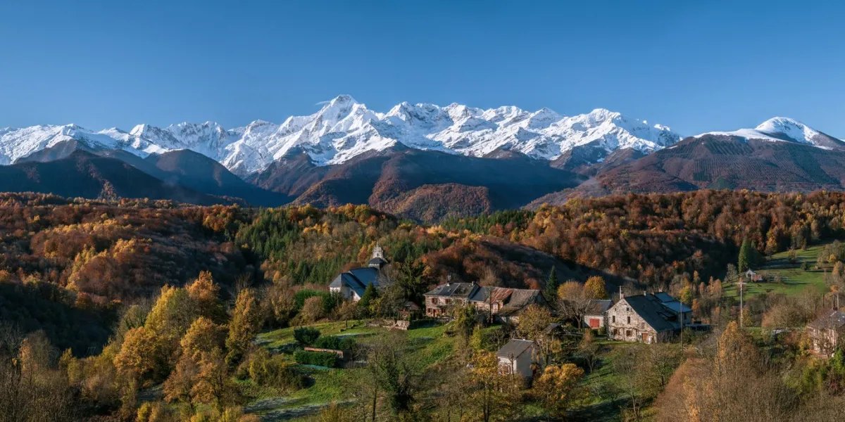 mountain village in autumn with first snow on the peaks in the background