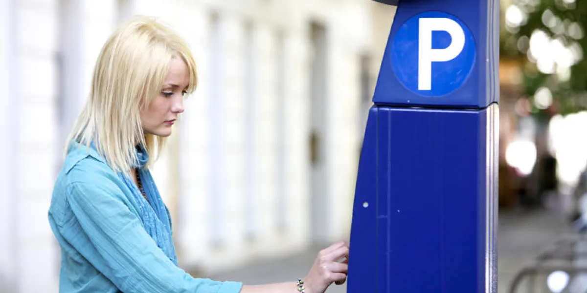 séduisante jeune femme payant pour le stationnement à un parcmètre à monnayeur
