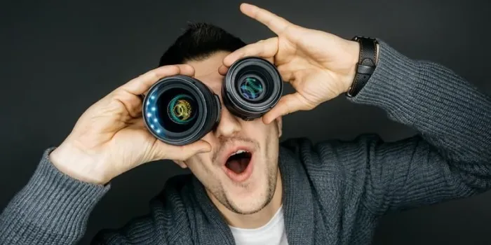 portrait of a male photographer he holds two lenses near the eyes funny facial expression
