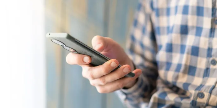 close-up image of male hands using smartphone at night on city shopping street, searching or social networks concept