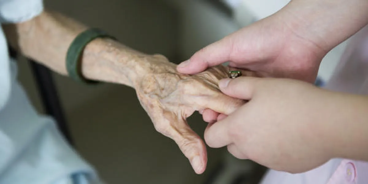 la main de la jeune fille touche et tient les mains ridées d'une vieille femme