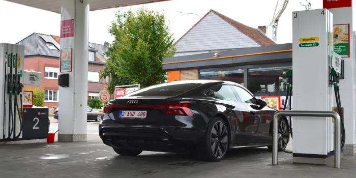 wilsele, vlaams-brabant, belgium - september 16, 2022  driver stationary black shiny audi e-tron gt parking at a gasoline lukoil refueling station to buy something in carrefour express shop