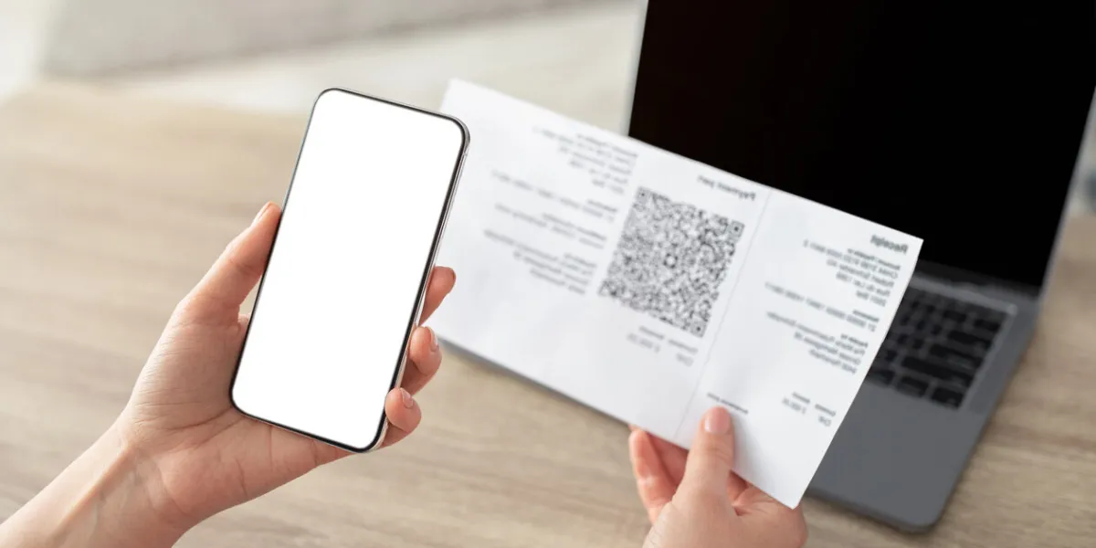 female hands holding smartphone and scanning the qr code from paper bill, cellphone with white blank screen paying online from home, modern technologies concept