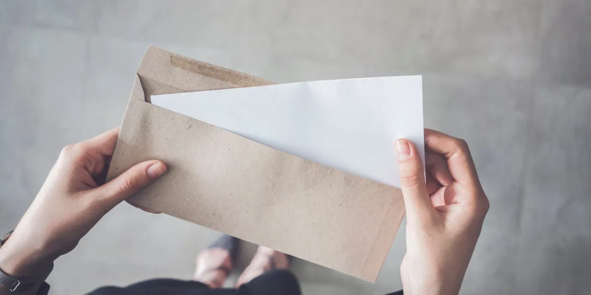 stand up woman holding white folded a4 paper and brown envelope