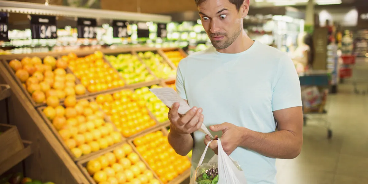surprised man reading receipt in grocery store