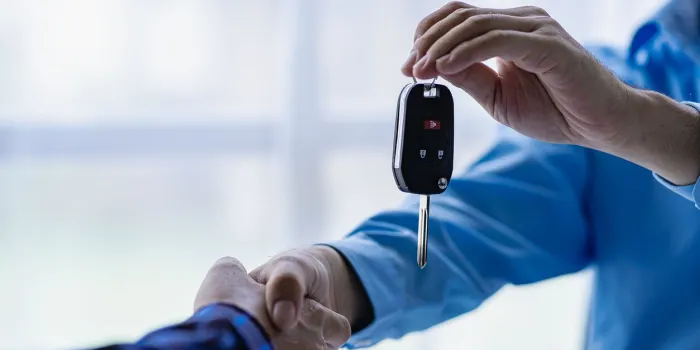 closeup of car sale and buyer shaking hands car salesman gives keys to buyer close-up of car dealership business giving keys to new owner and handshake in office