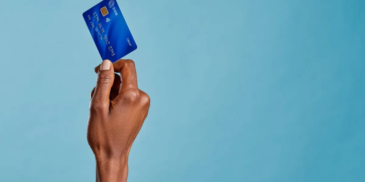 close up of african woman hand holding bank credit card to make a payment with copy space black woman hand holding credit card for financial transaction or contact less payment isolated on blue background african american woman showing debit card