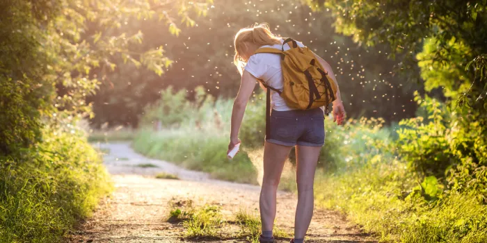 woman applying insect repellent against mosquito and tick on her leg during hike in nature skin protection against insect bite