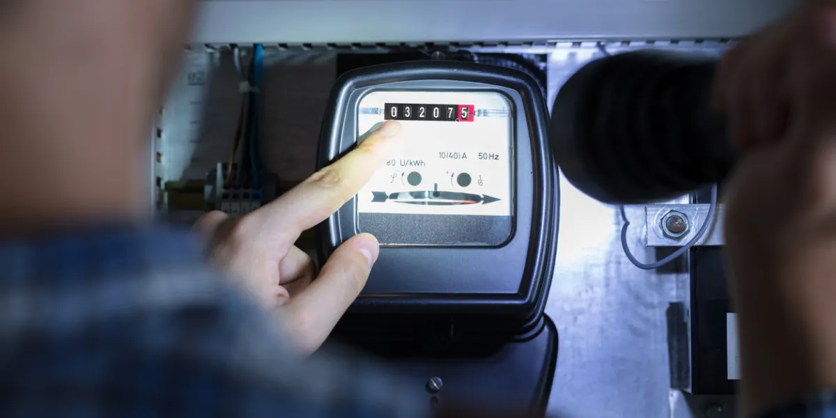 person's finger pointing to electric meter reading using flash light