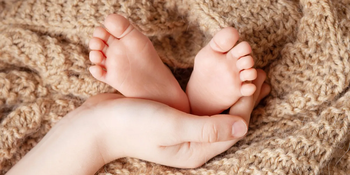 baby feet in brother hands tiny newborn baby's feet closeup happy family concept