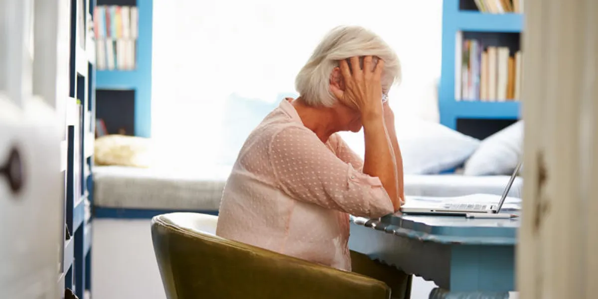 stressed senior woman at desk in home office with laptop