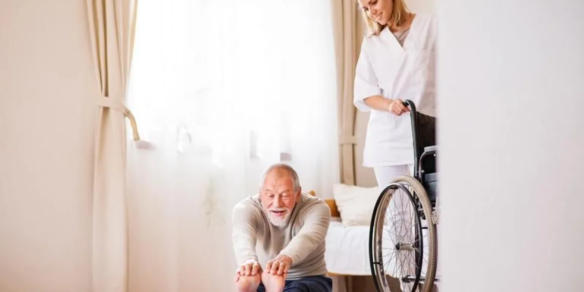 health visitor and a senior man during home visit a nurse or a physiotherapist helping a senior man exercise