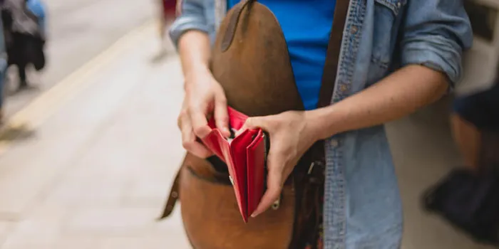 a young woman is standing in the street and is opening her purse to make a purchase