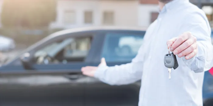 one man holding a car key next to his vehicle , main focus on the hand
