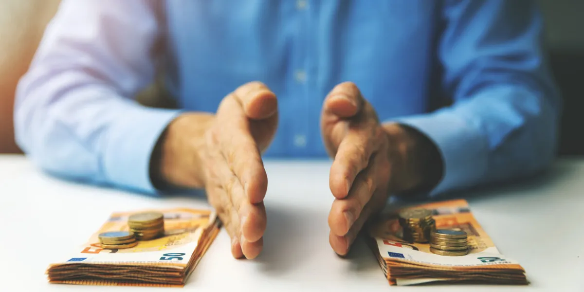 finance management and budget planning concept - businessman splitting the money on the table