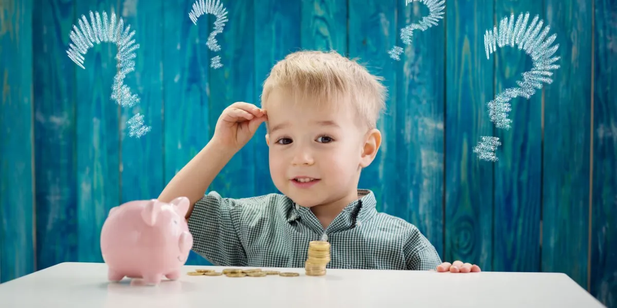 three years old child sitting at the table with money and piggybank happy boy with euro coins future childhood and education investment finance and savings concept