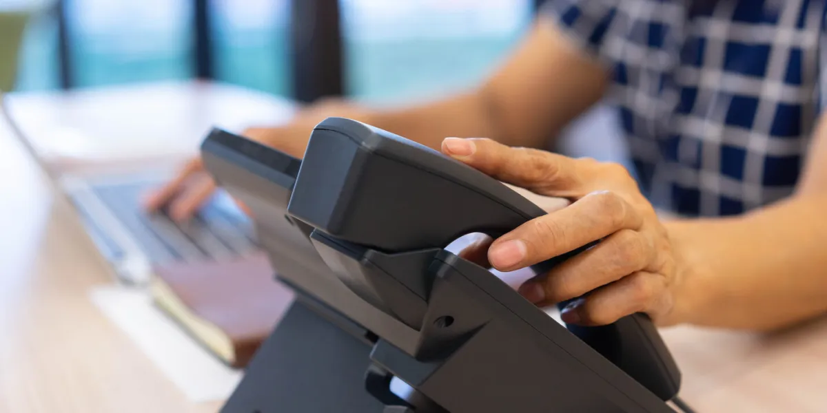 close up senior woman hand touching on handset telephone to calling to colleagues or answering ringing call from customer at office for communication and contact us concept