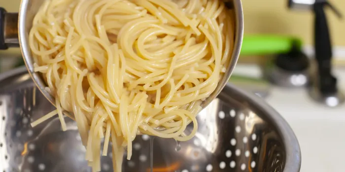 preparing to drain cooked spaghetti in a sink