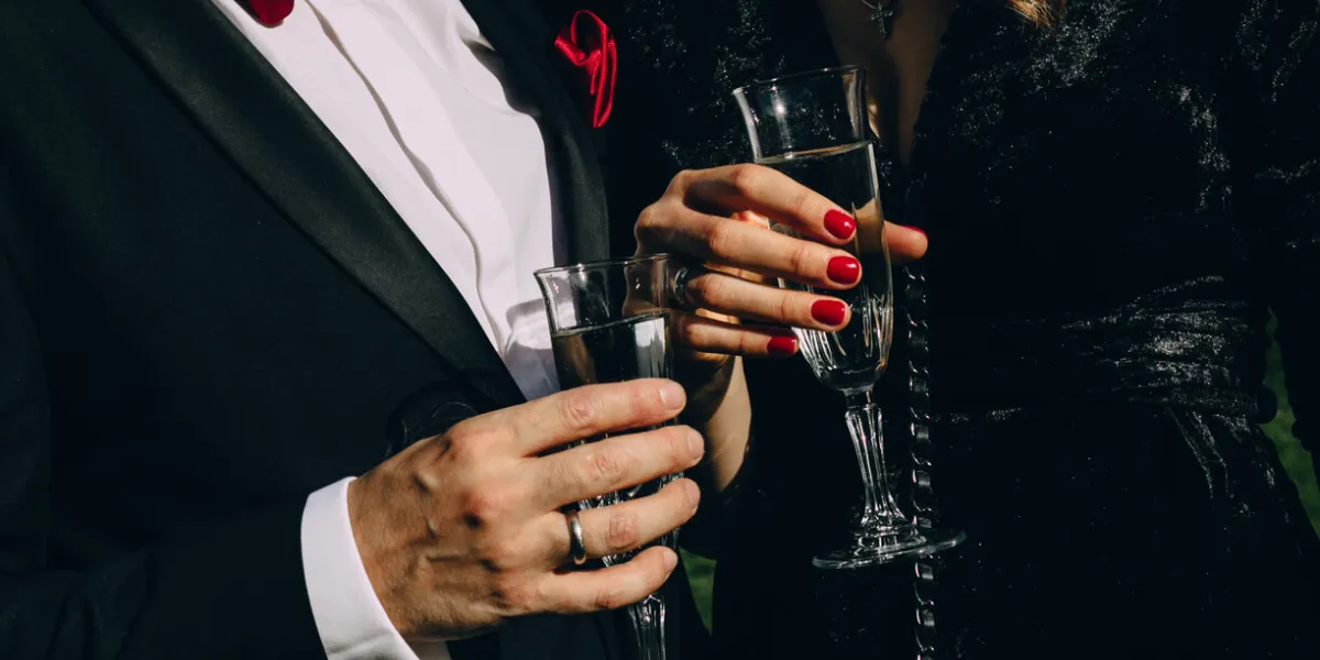 party style man in black suit red butterfly woman in black clothes red manicure drink champagne