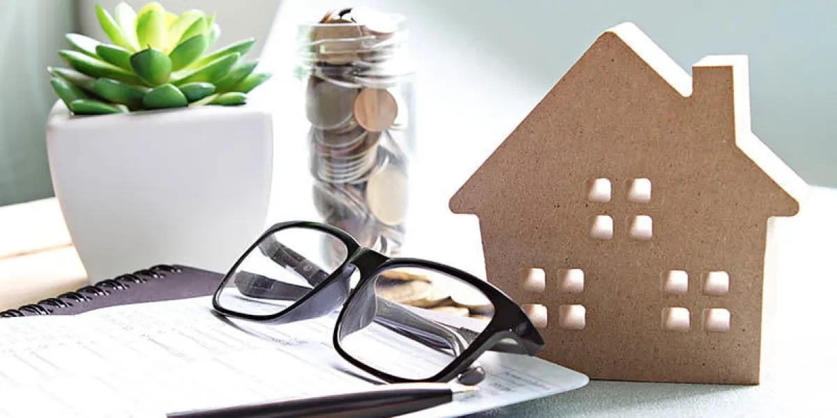 business, finance, saving money, banking, property loan or mortgage concept   wood house model, coins, eyeglasses and saving account book or financial statement on office desk table