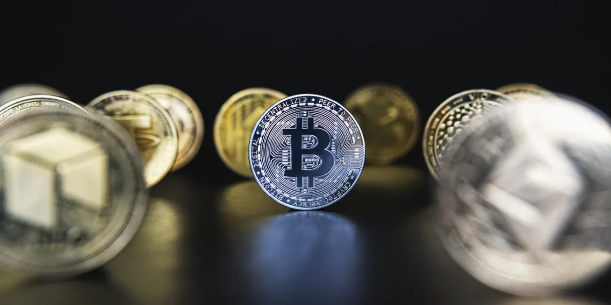 silver bitcoin next to many cryptocurrency coins like defocused ethereum, neo, tether on black background central composition, low key photo for banners and news about btc crypto