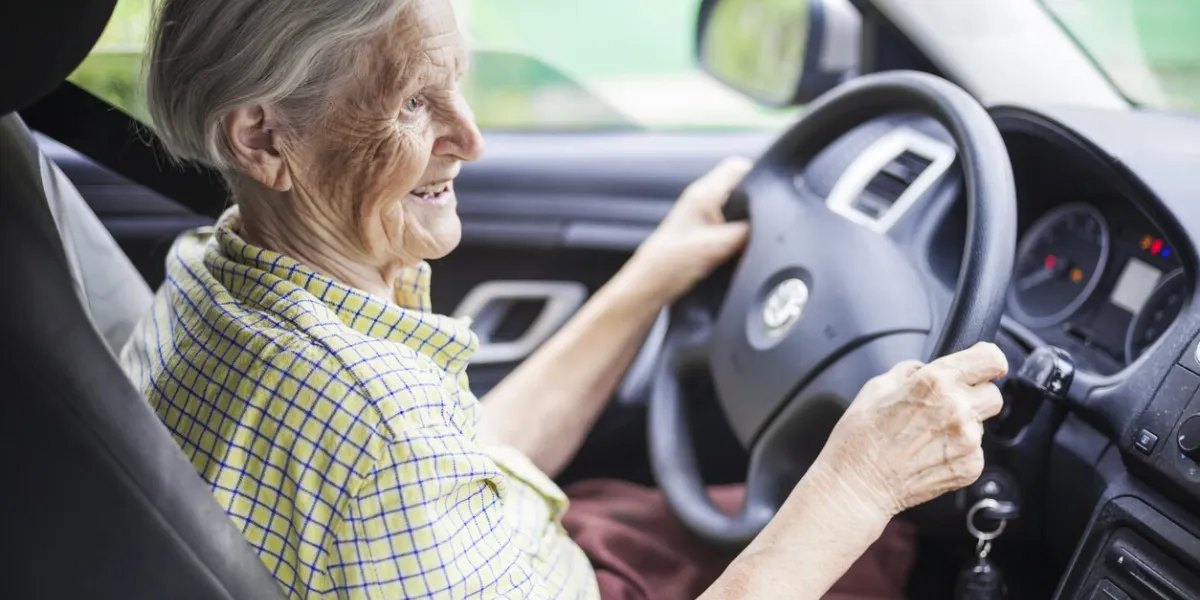 senior woman driving a car and smiling