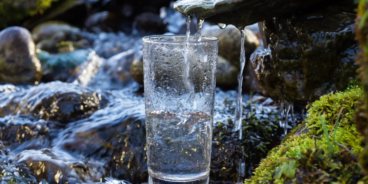 natural drinking water is being poured into glass