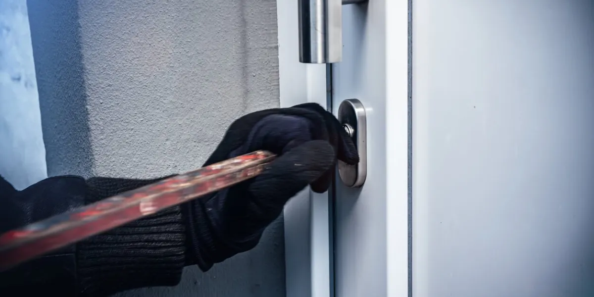 masked burglar with crowbar breaking and entering into a victim's home motion blur selective focus