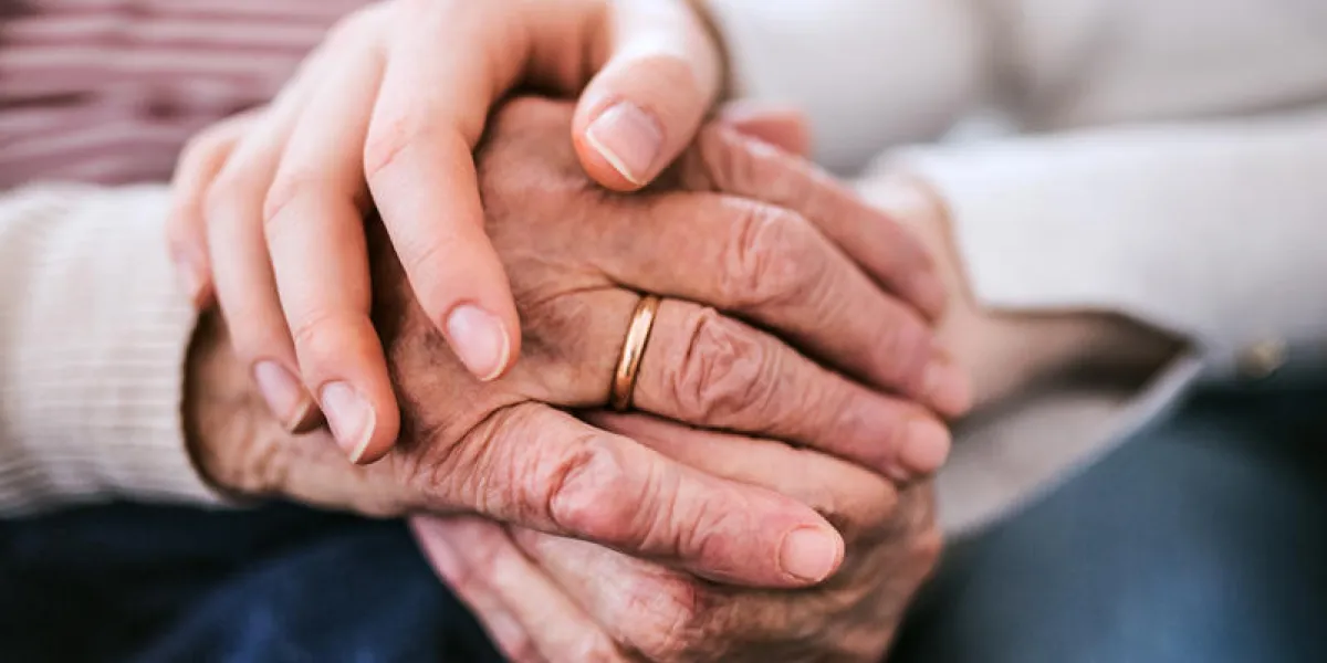 unrecognizable teenage girl with grandmother at home, holding hands family and generations concept close up