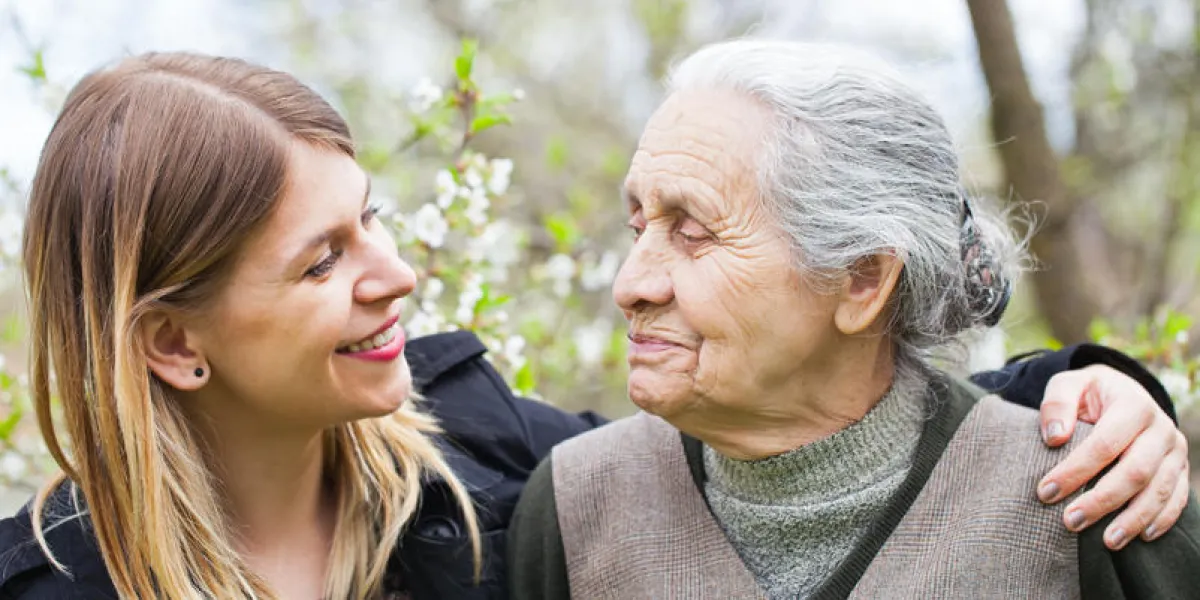 picture of a happy elderly woman with her cheerful carer outdoor springtime