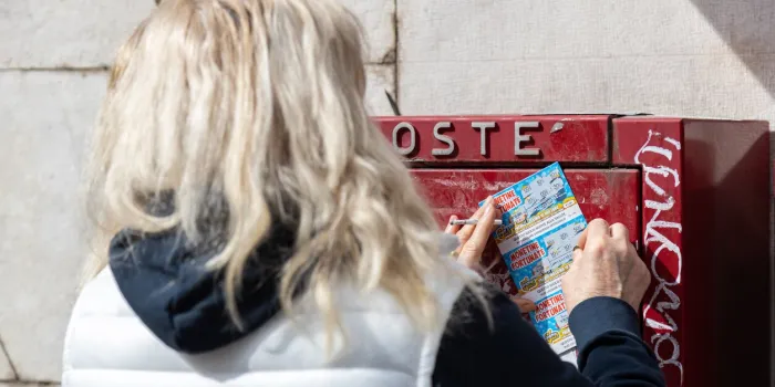 padua, veneto, italy - mar 11th, 2023  woman scraping a scratch card with a coin