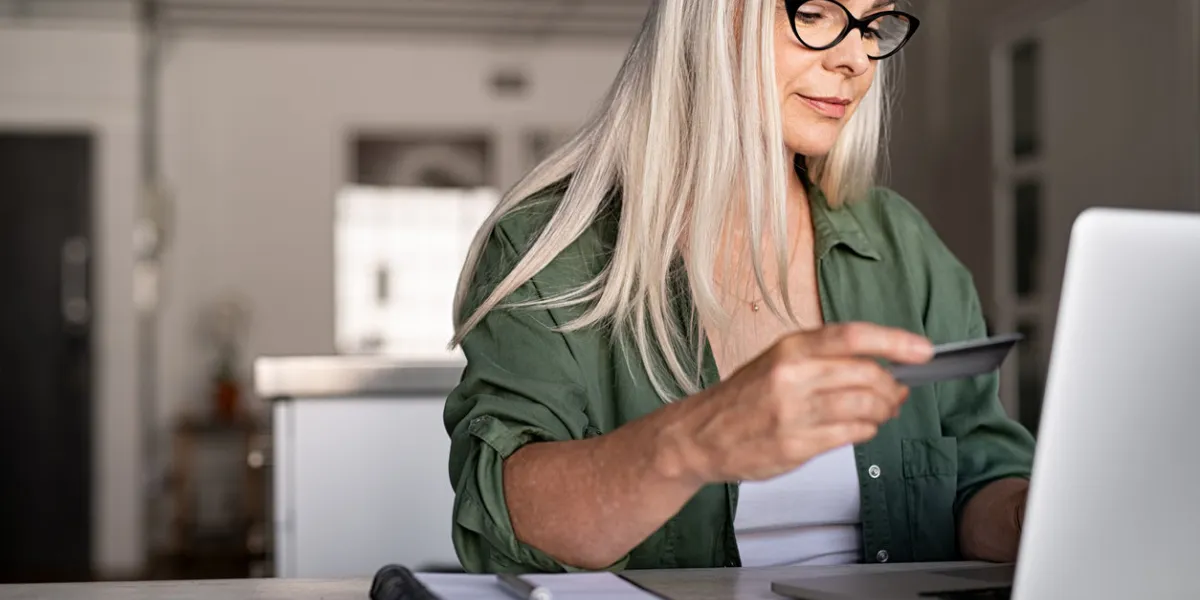 mature woman using credit card making online payment at home successful old woman doing online shopping using laptop closeup of retired fashionable lady holding debit card for internet banking account