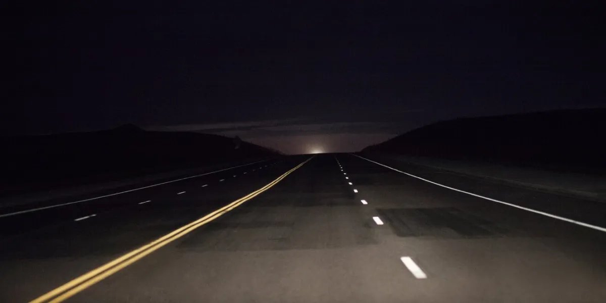 dark country road in the wyoming countryside with the moon just peeking above the horizon
