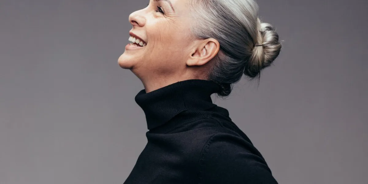 side view of senior woman laughing on gray background profile view of mature woman in black casuals looking happy