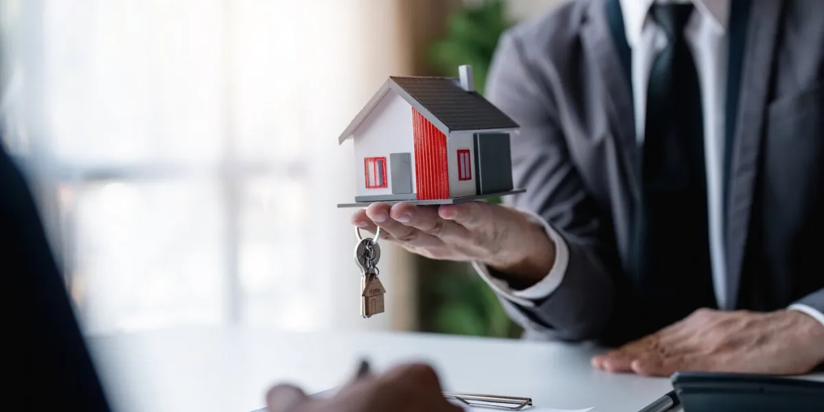 real estate broker agent presenting and consult to customer to decision making sign insurance form agreement, home model, concerning mortgage loan offer for and house insurance